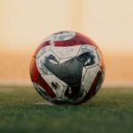 Close-up of a soccer ball on a grassy field in Libya during sunset.