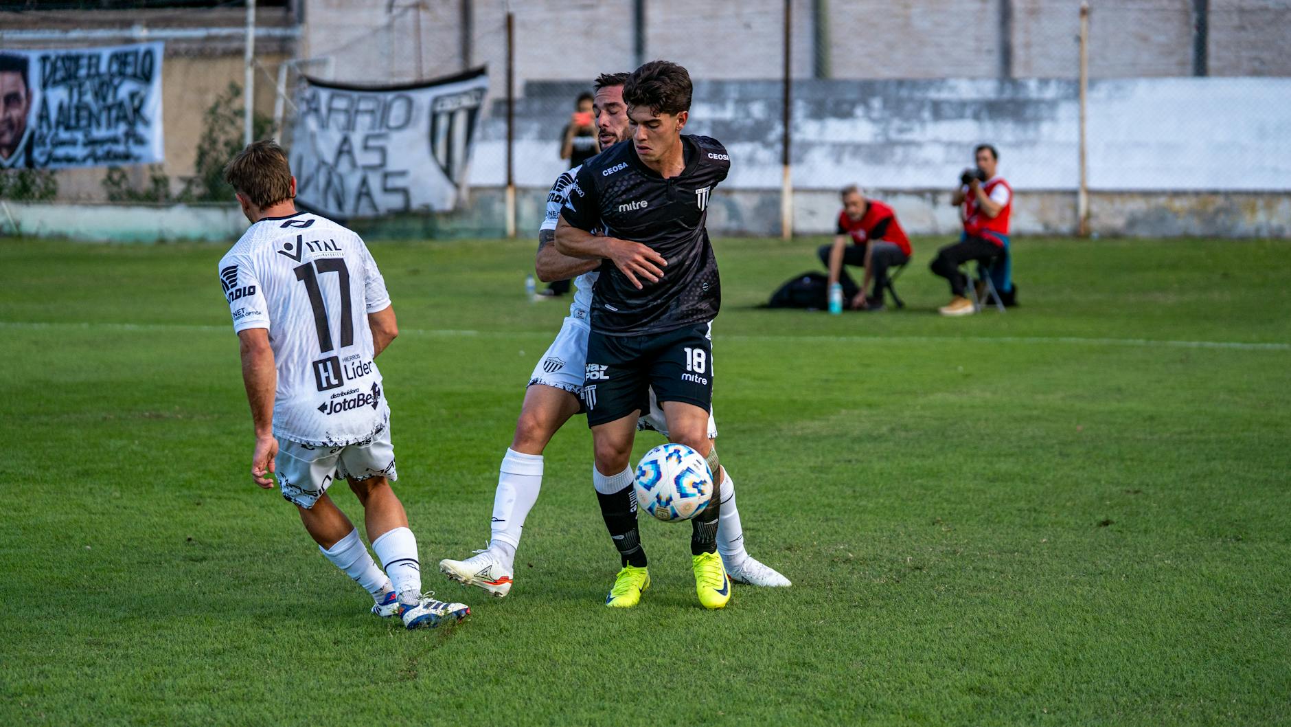 Two soccer players competing intensely on a green field during a daytime match.