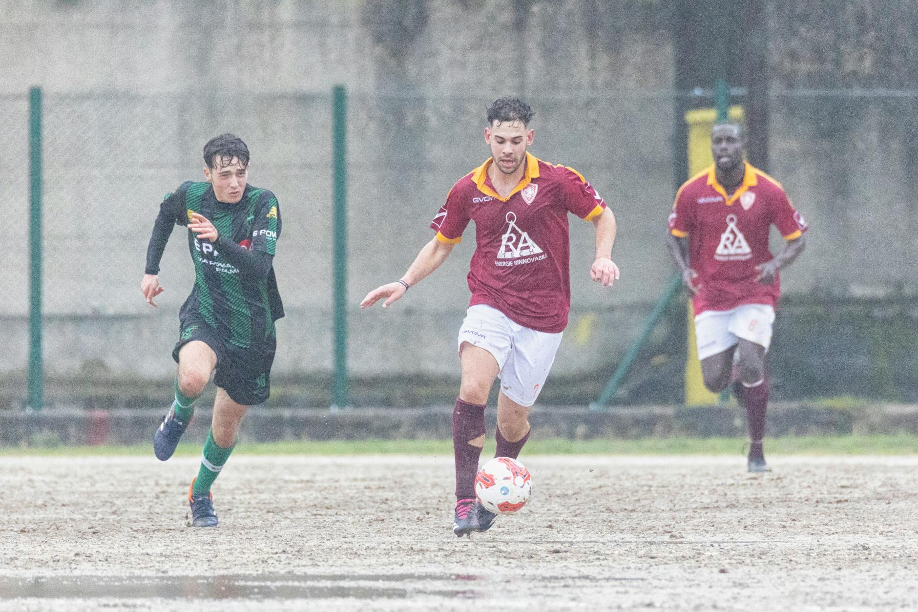 Athletes play soccer in rainy Delianuova, Calabria, Italy, showcasing teamwork and dedication.