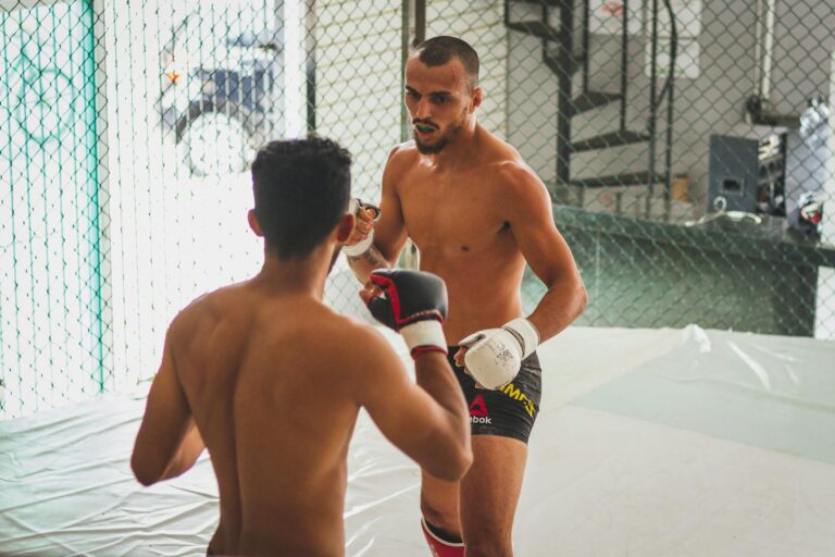 Two men sparring in a kickboxing match inside an MMA training ring.