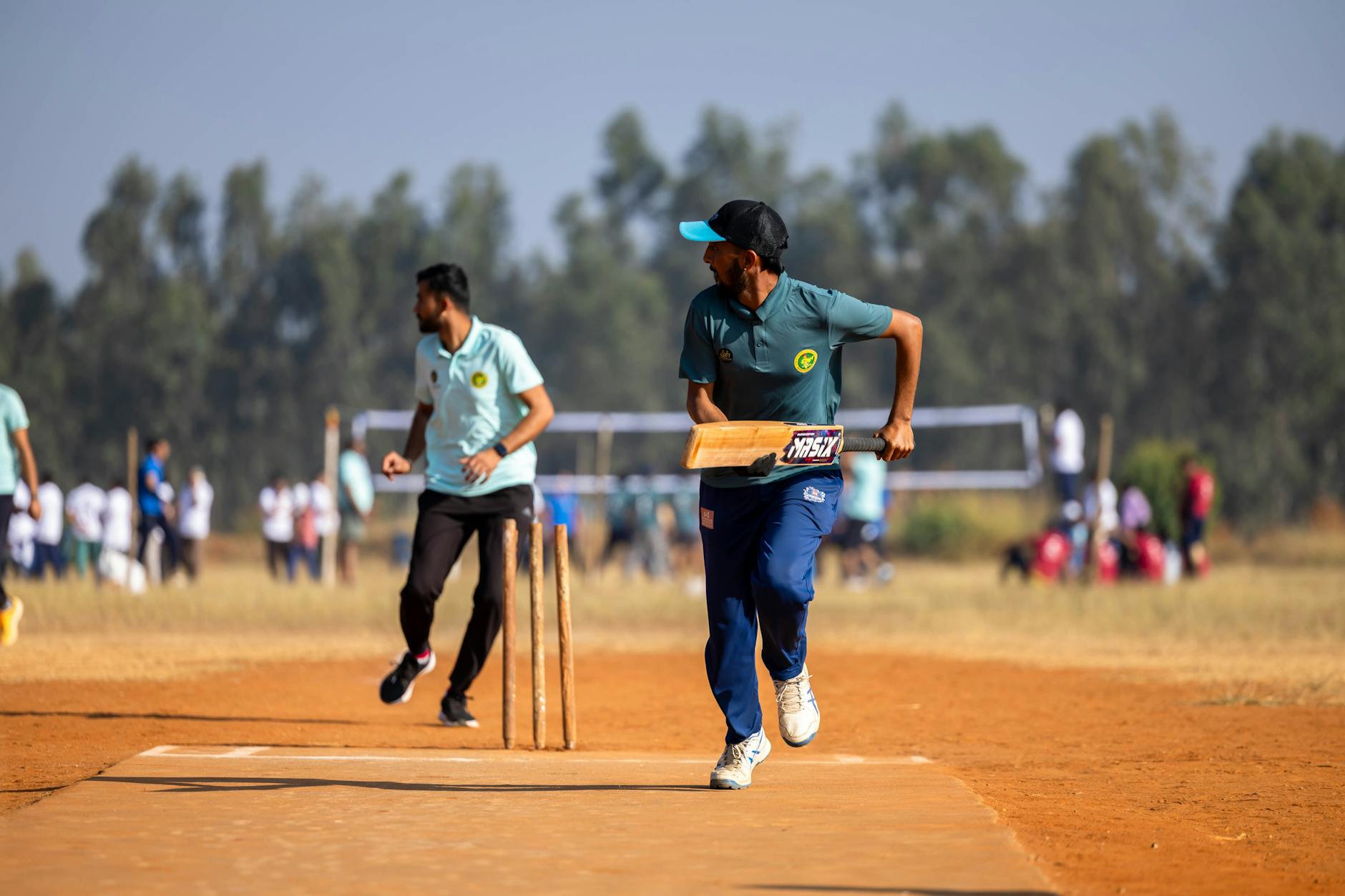 Players in action during a thrilling outdoor cricket match with spectators in the background.