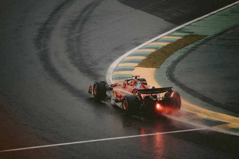 Exciting scene of a red race car taking a sharp turn on a wet track, showcasing speed and precision.