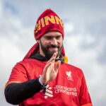 Liverpool FC player joyfully celebrates victory under the clear sky.