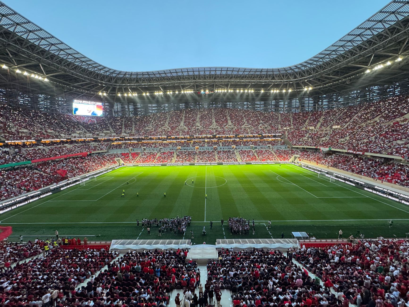 A packed football stadium in Morocco buzzing with excitement during a match, showcasing vibrant crowds and dazzling lights.
