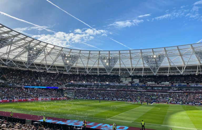A packed London Stadium hosts a thrilling soccer match, with vibrant atmosphere and engaged crowd.