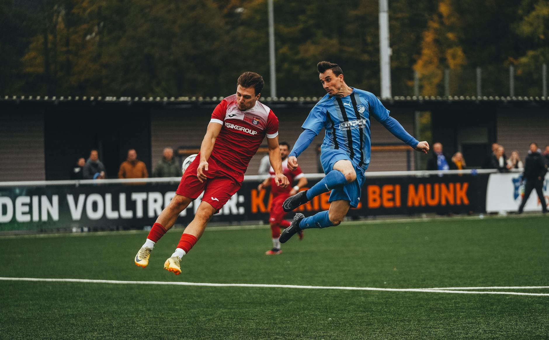 Two soccer players compete fiercely during a match on a green field.