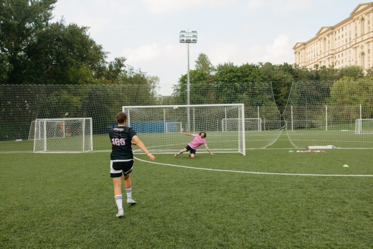 A soccer player takes an action-packed penalty shot towards the goalkeeper on a field.