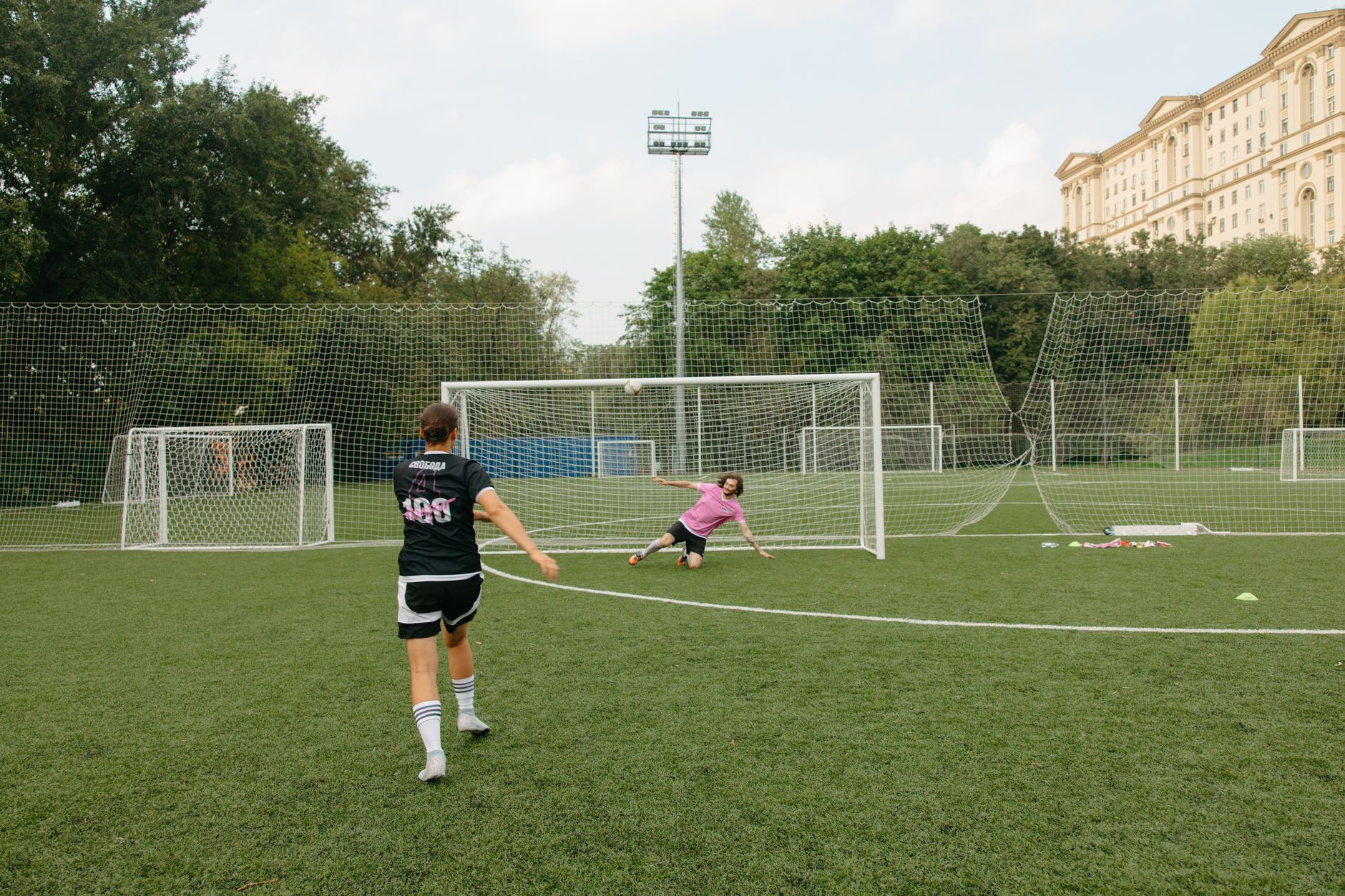 A soccer player takes an action-packed penalty shot towards the goalkeeper on a field.
