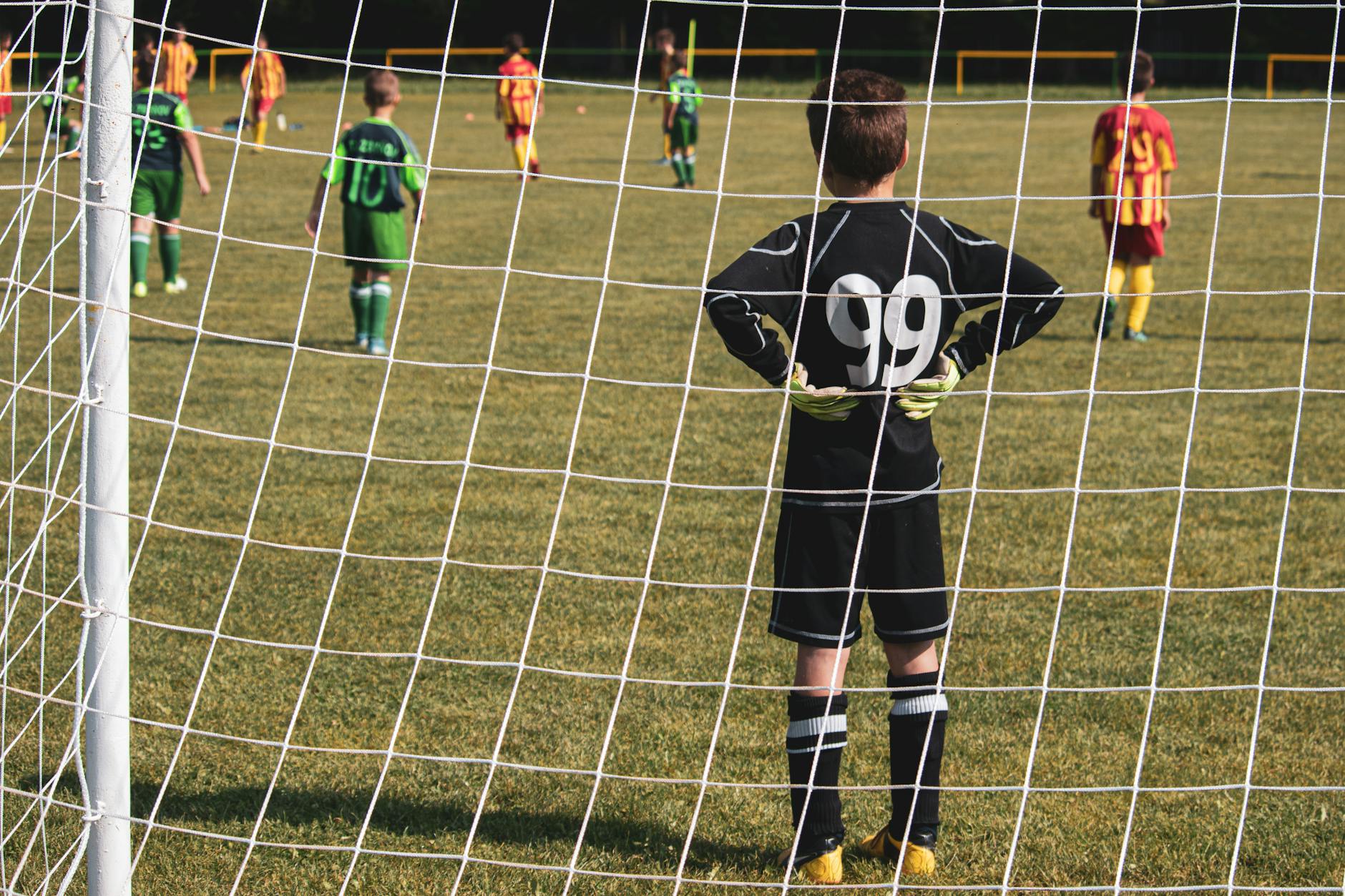 A young goalkeeper stands ready while teammates prepare for the soccer match.
