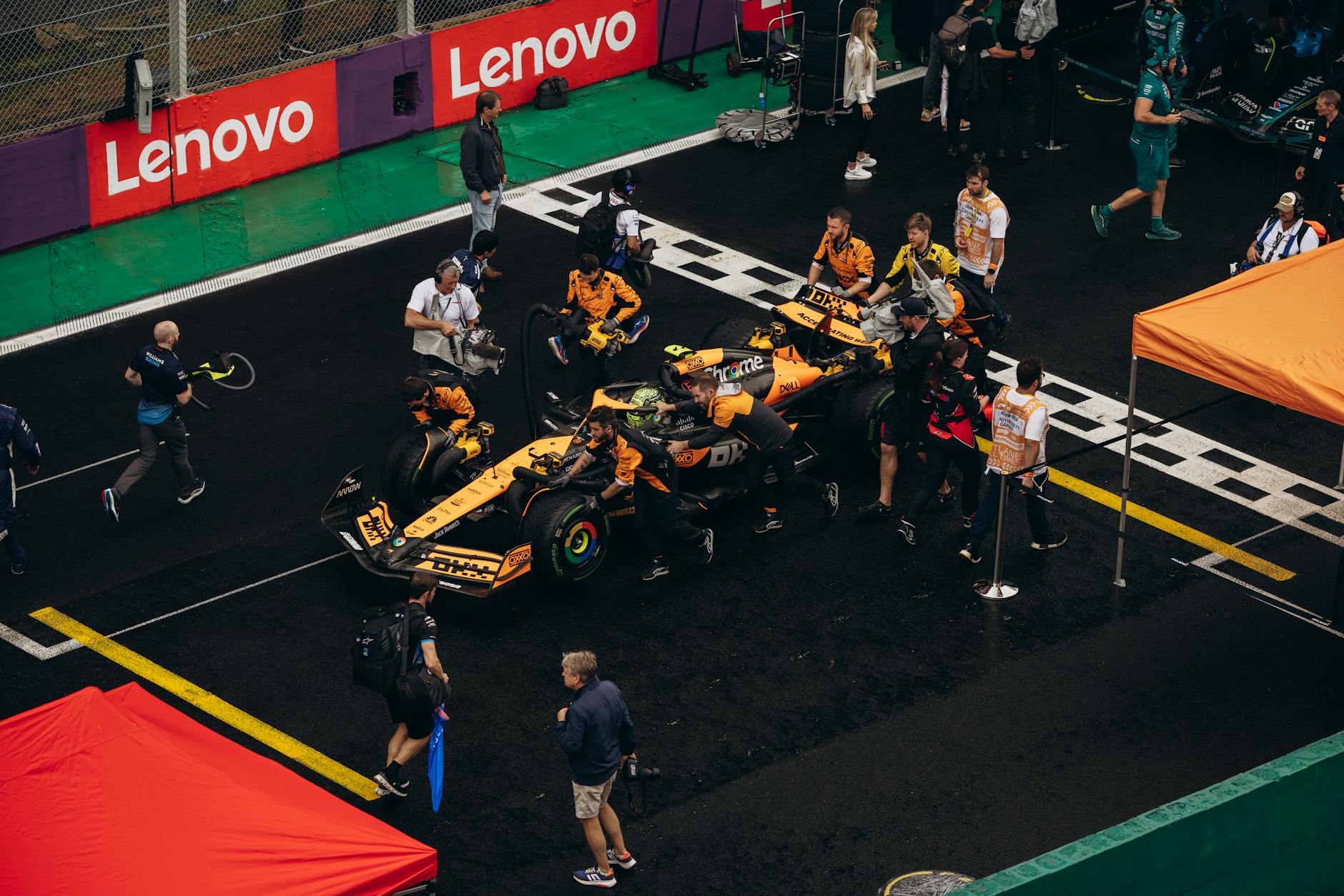 A Formula 1 pit crew preparing a car for the race on a rainy day, teamwork in action.