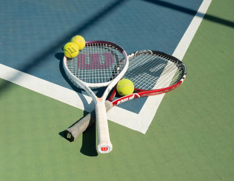 Two tennis rackets and balls on a sunlit court in San Francisco.