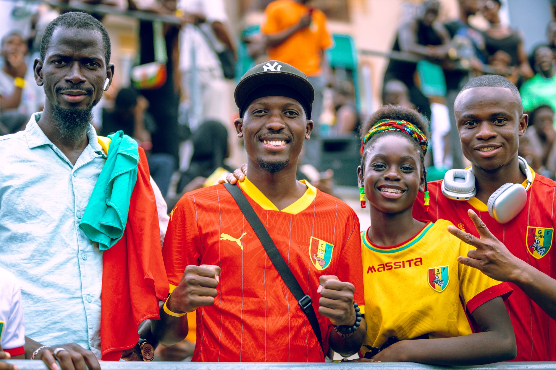 Group of four joyful soccer fans in vibrant jerseys, celebrating outdoors.