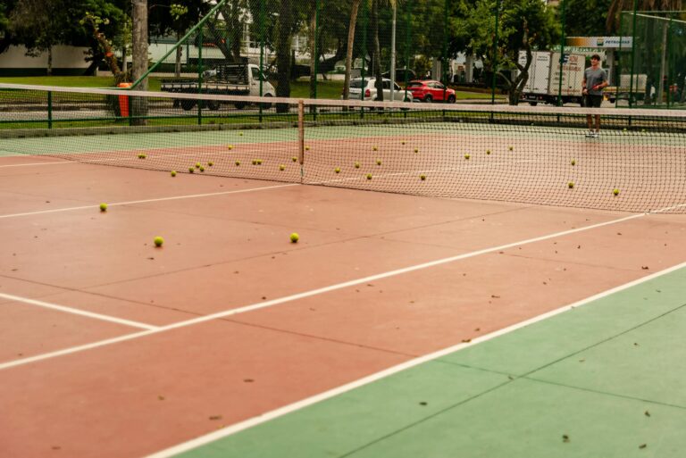 Tennis court with scattered tennis balls across the surface, ready for play.