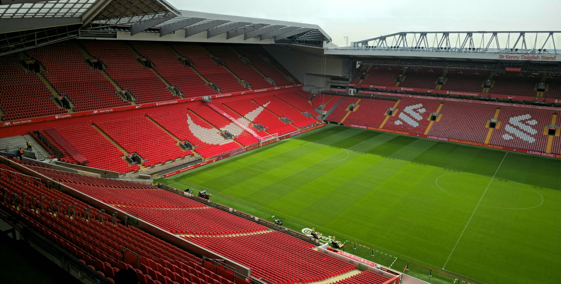 Aerial view of Anfield Stadium, Liverpool, showcasing its empty red seats and green pitch.