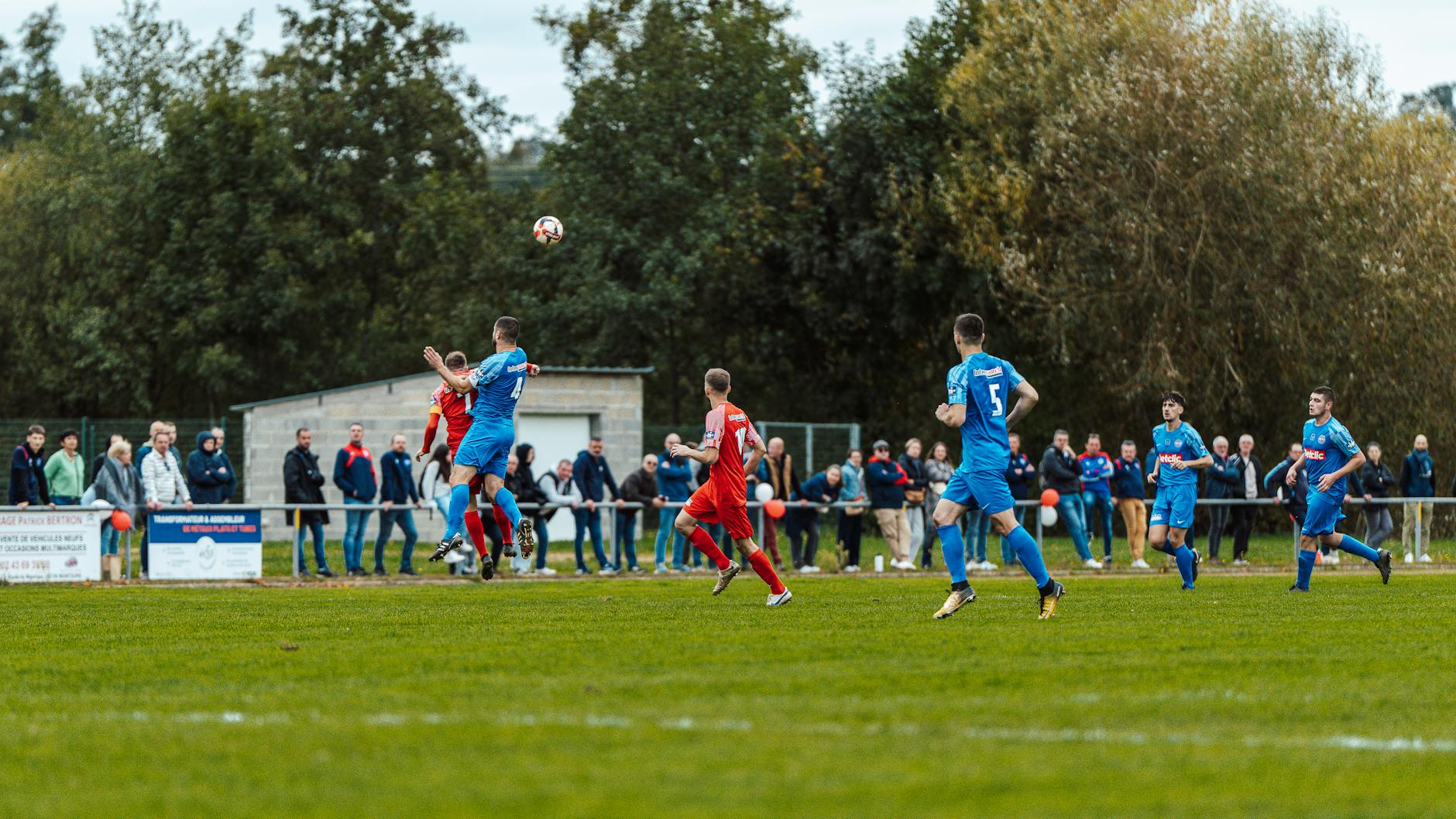 Players in blue and red compete intensely on a football field in France, capturing the spirit of the game.