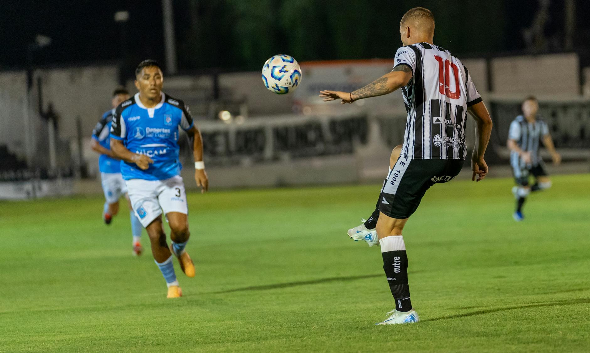 Soccer match intensifies under stadium lights as players compete fiercely on the field.