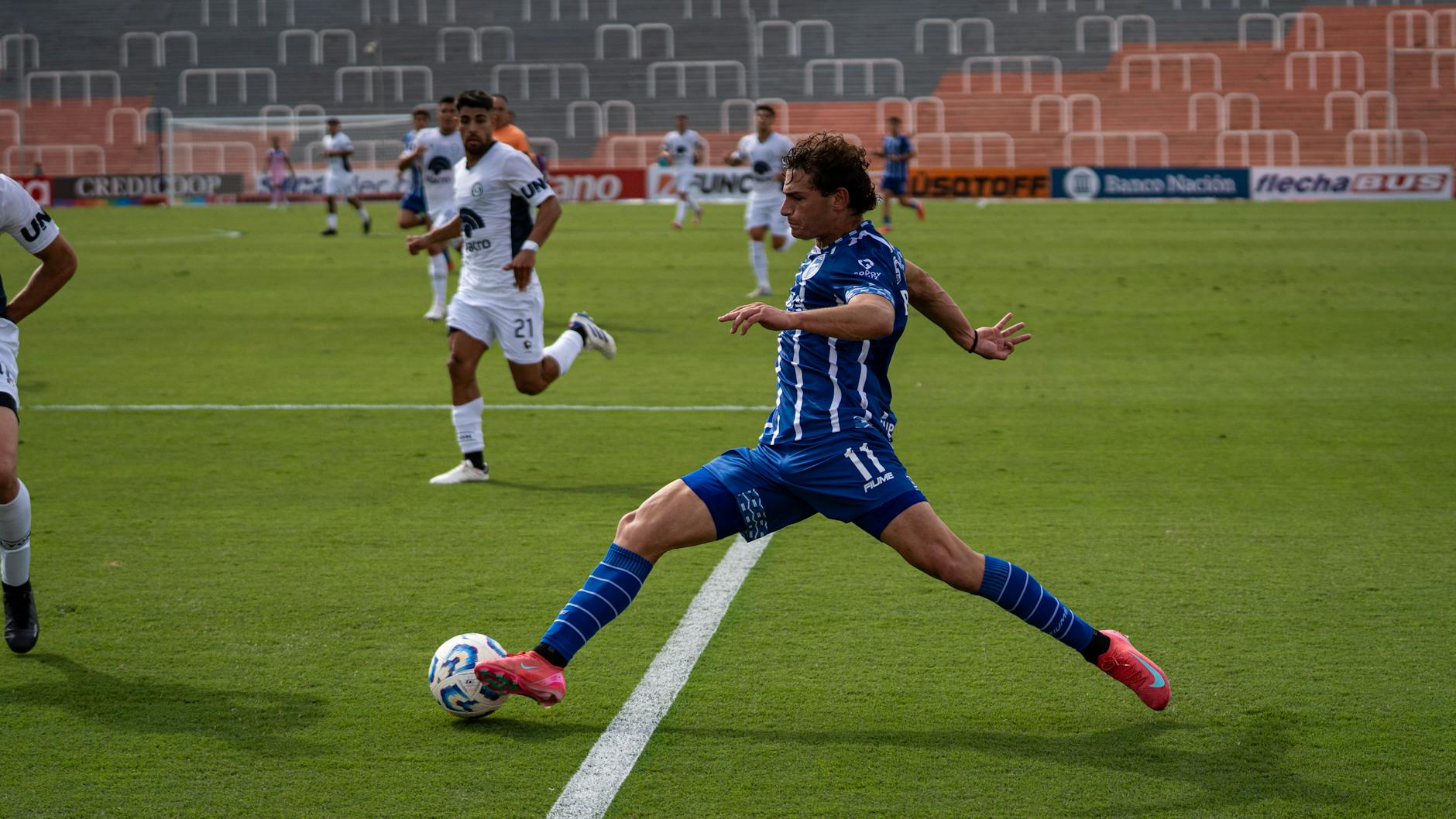 Dynamic soccer match featuring players in blue and white uniforms during a sunny day.