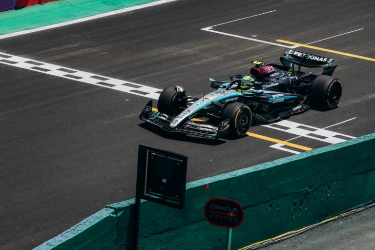 High-speed Formula 1 car crossing the finish line on a race track during the day.