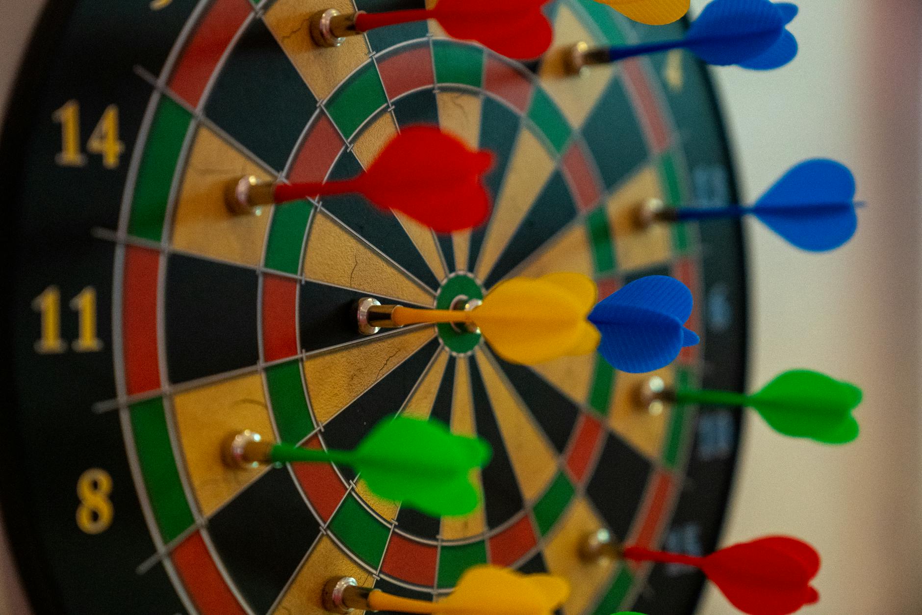 A close-up of vibrant colored darts on a dartboard, representing focus and precision in sports.