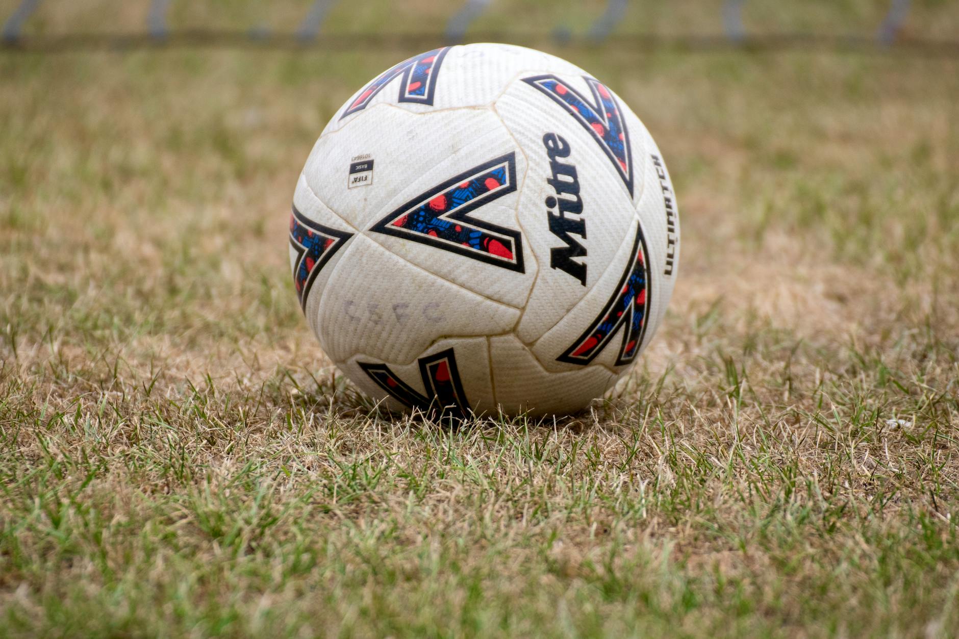Close-up of a soccer ball on dry grass in Tipton, England. Perfect for sports and recreation themes.
