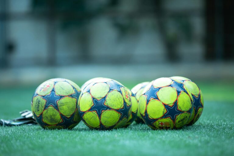 Four vibrant soccer balls resting on a green grass field.