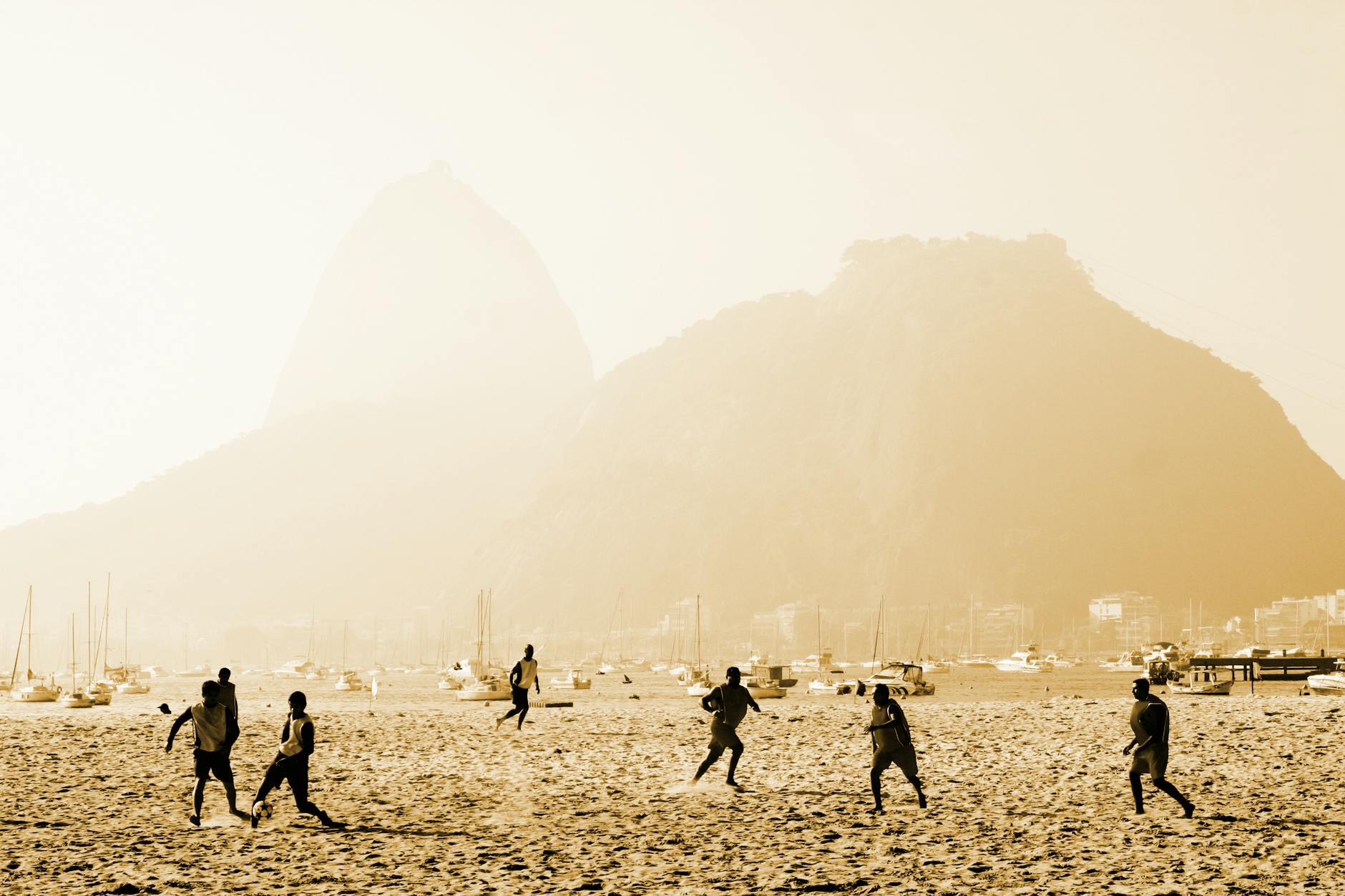 Dynamic beach soccer game with Sugarloaf Mountain in Rio de Janeiro.