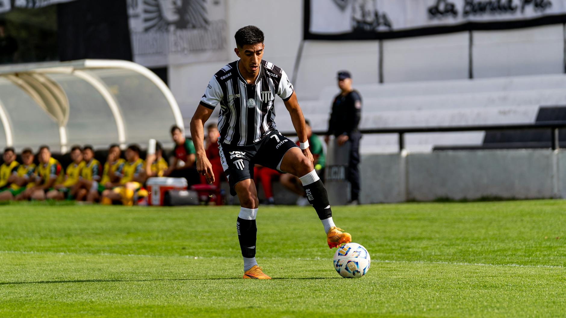 Professional soccer player dribbling during an outdoor match, capturing athletic skill and focus.