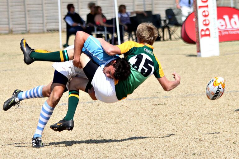 Two rugby players collide mid-air in an action-packed outdoor rugby match.