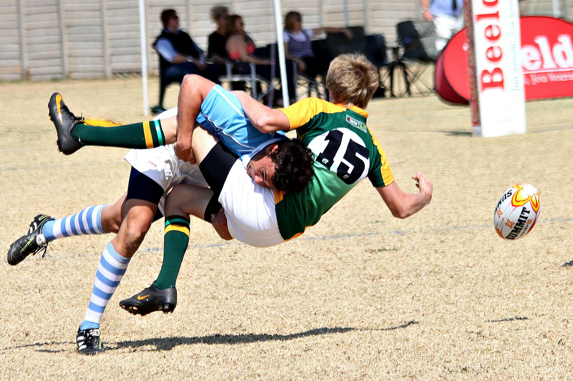 Two rugby players collide mid-air in an action-packed outdoor rugby match.