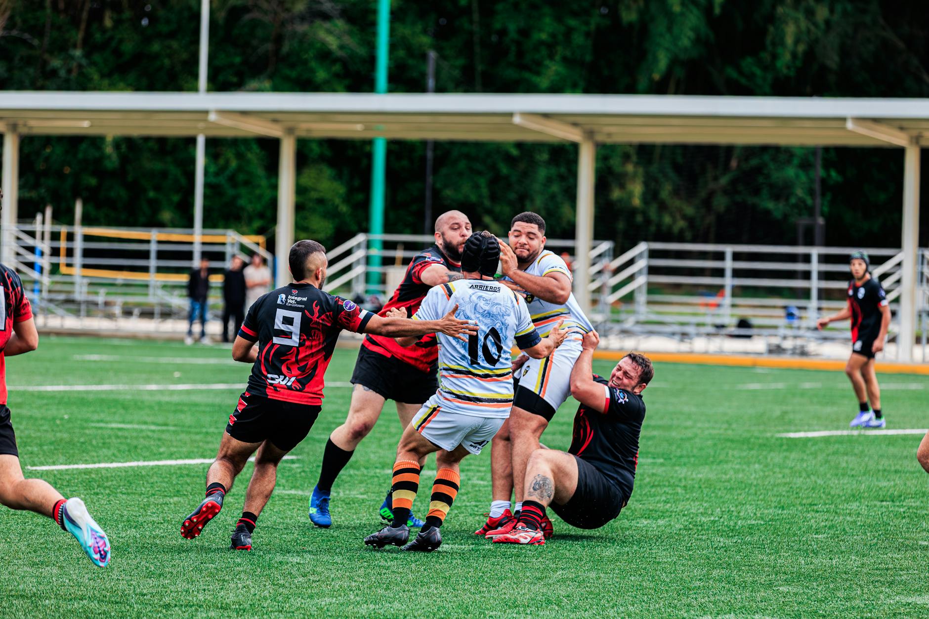 Rugby players in a dynamic tackle during an outdoor match on a green field.