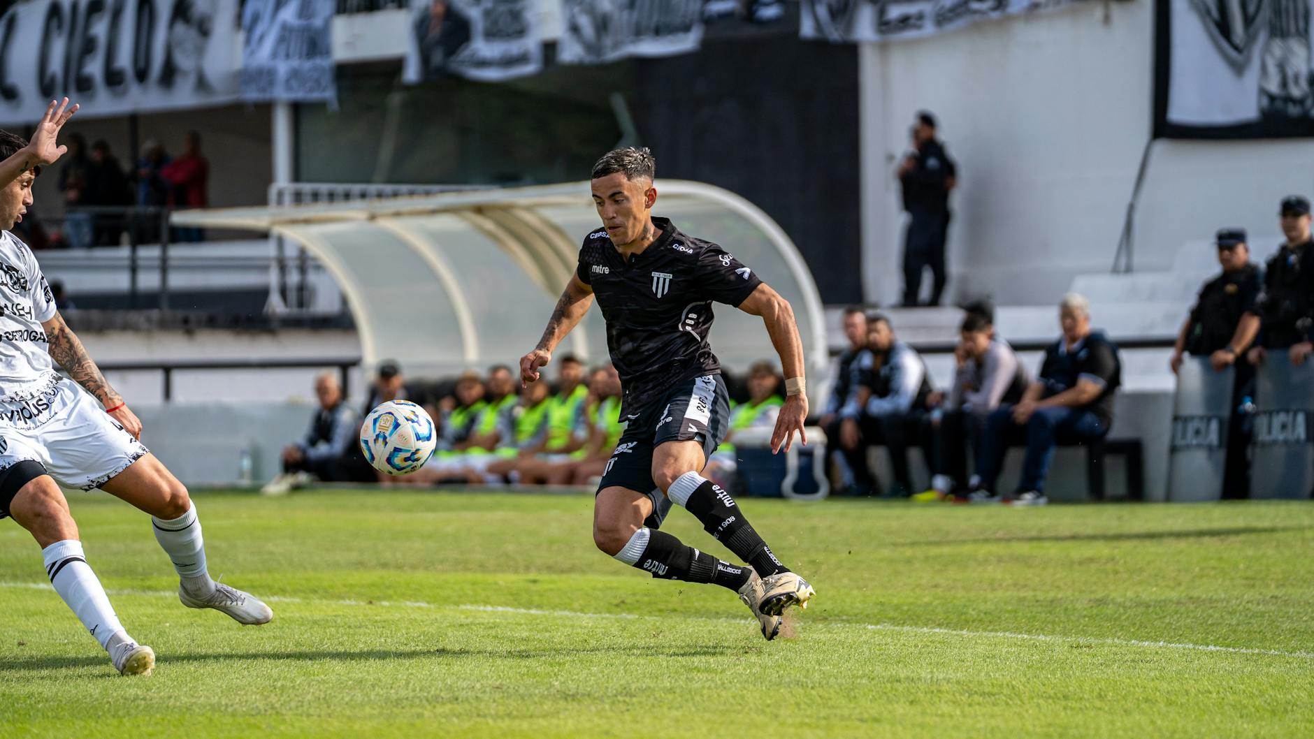 Soccer players in action during a competitive match on a sunny day.