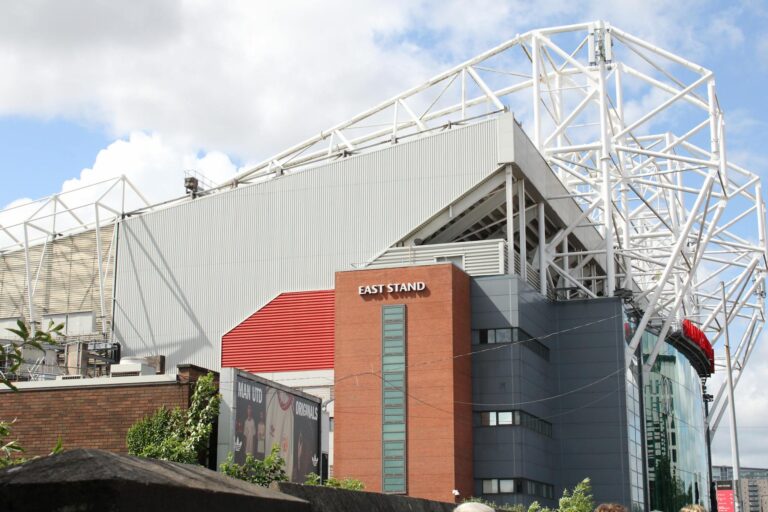 Exterior view of the East Stand at Old Trafford Stadium on a sunny day.