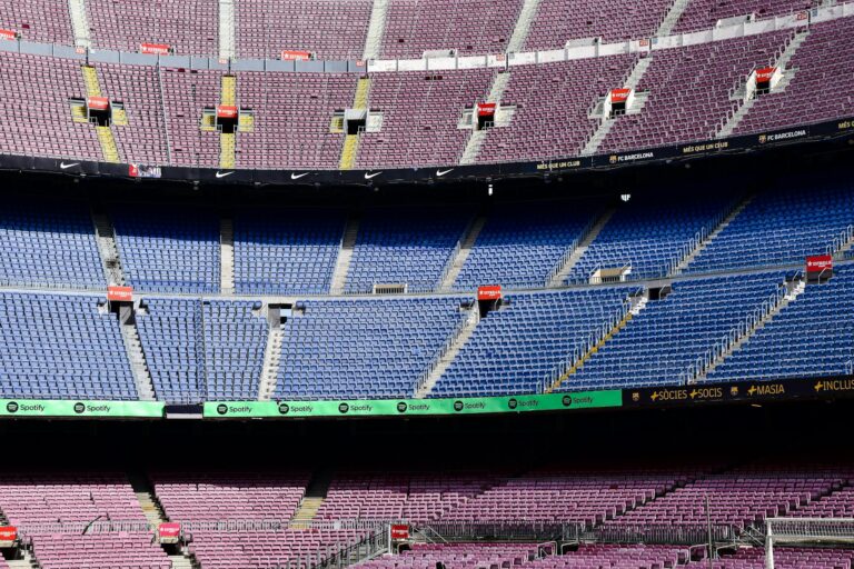 Wide-angle view of the empty stands at Camp Nou Stadium in Barcelona displaying vibrant seat colors.