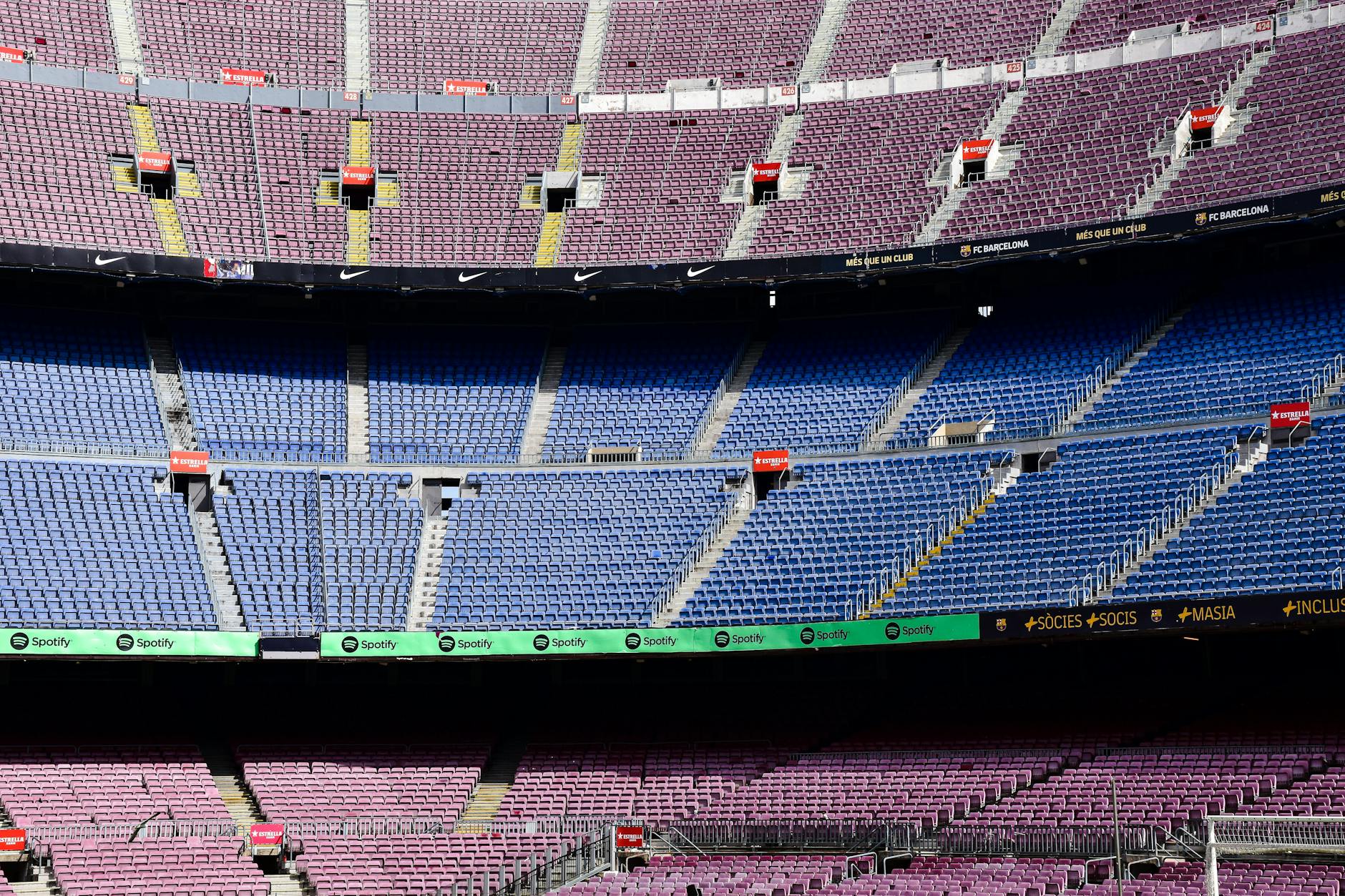 Wide-angle view of the empty stands at Camp Nou Stadium in Barcelona displaying vibrant seat colors.