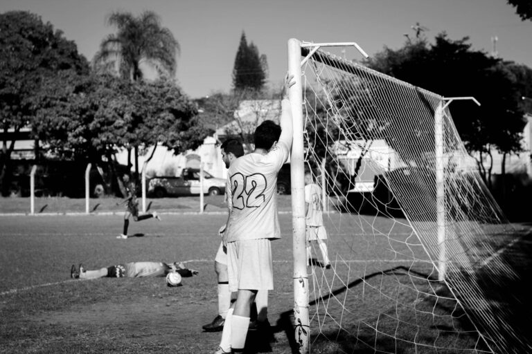 A candid black and white photo capturing players during a soccer match in Itapira, Brazil.