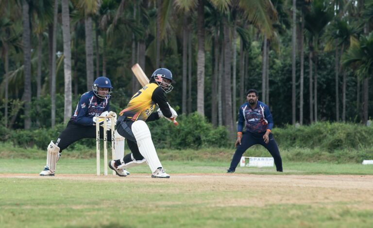 Dynamic cricket action featuring a batsman playing a shot in a lush outdoor setting.