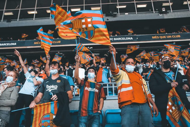 Fans enthusiastically wave FC Barcelona flags at a football match, showcasing team spirit and unity.