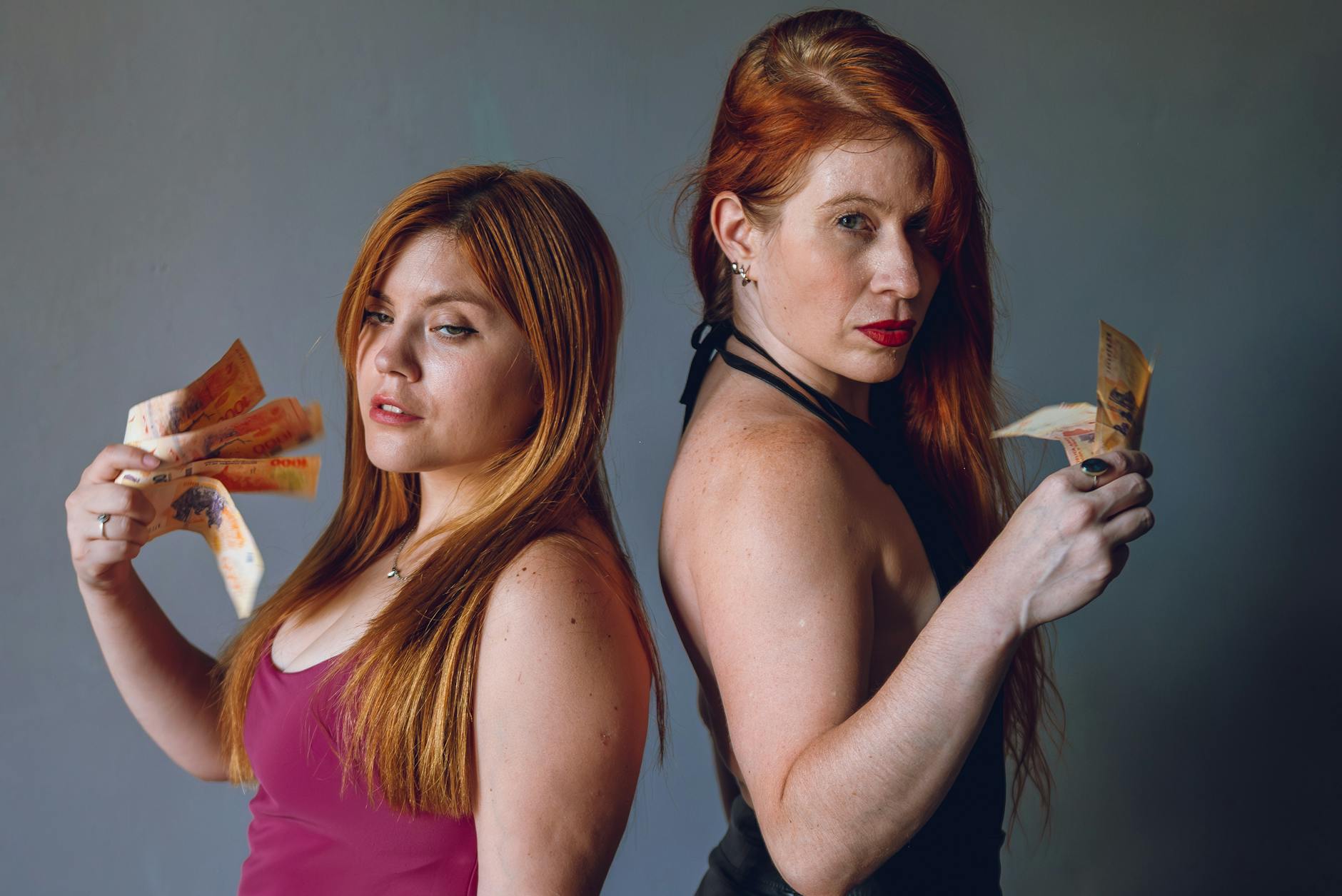 Two women holding Argentine pesos, showcasing currency in Buenos Aires.