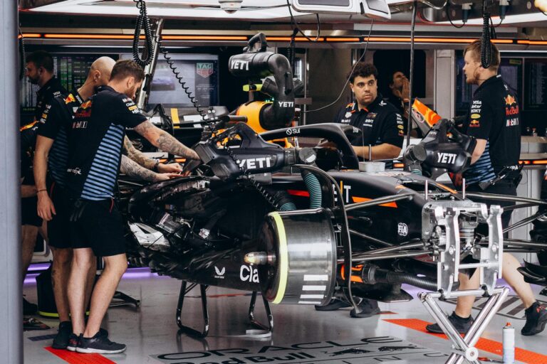 Formula 1 team mechanics work on a race car in the garage, preparing for the competition.