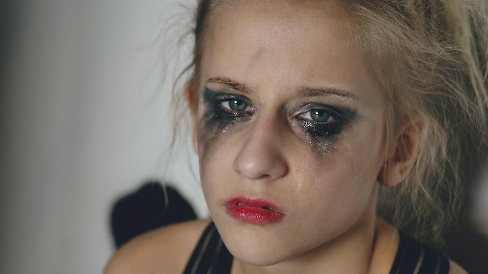 Close-up portrait of a woman with messy makeup and tears, conveying deep emotion.