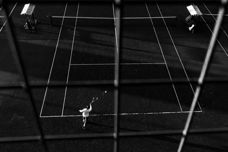 Black and white photo of a tennis match in Buenos Aires, capturing dynamic motion and shadow play.