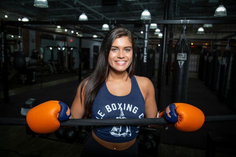Confident woman in a gym wearing boxing gloves, ready for training.