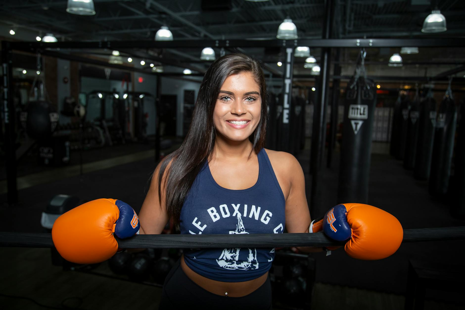 Confident woman in a gym wearing boxing gloves, ready for training.