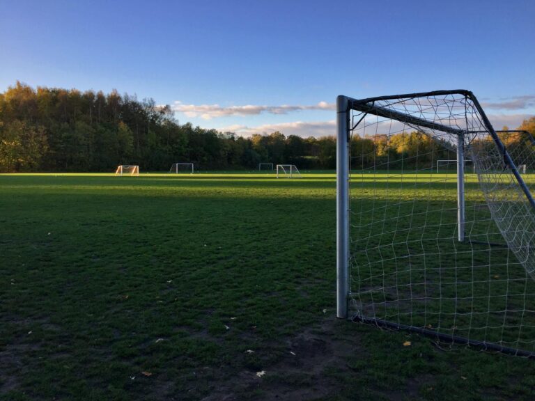 Peaceful soccer field at sunset, with green grass and goalposts, ideal for recreation.