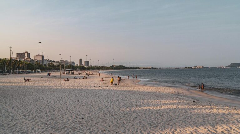 People enjoying a sunny day on Flamengo Beach in Rio de Janeiro, with city skyline views.