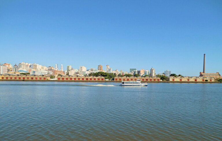 Scenic view of Porto Alegre's waterfront with city skyline and clear blue sky.
