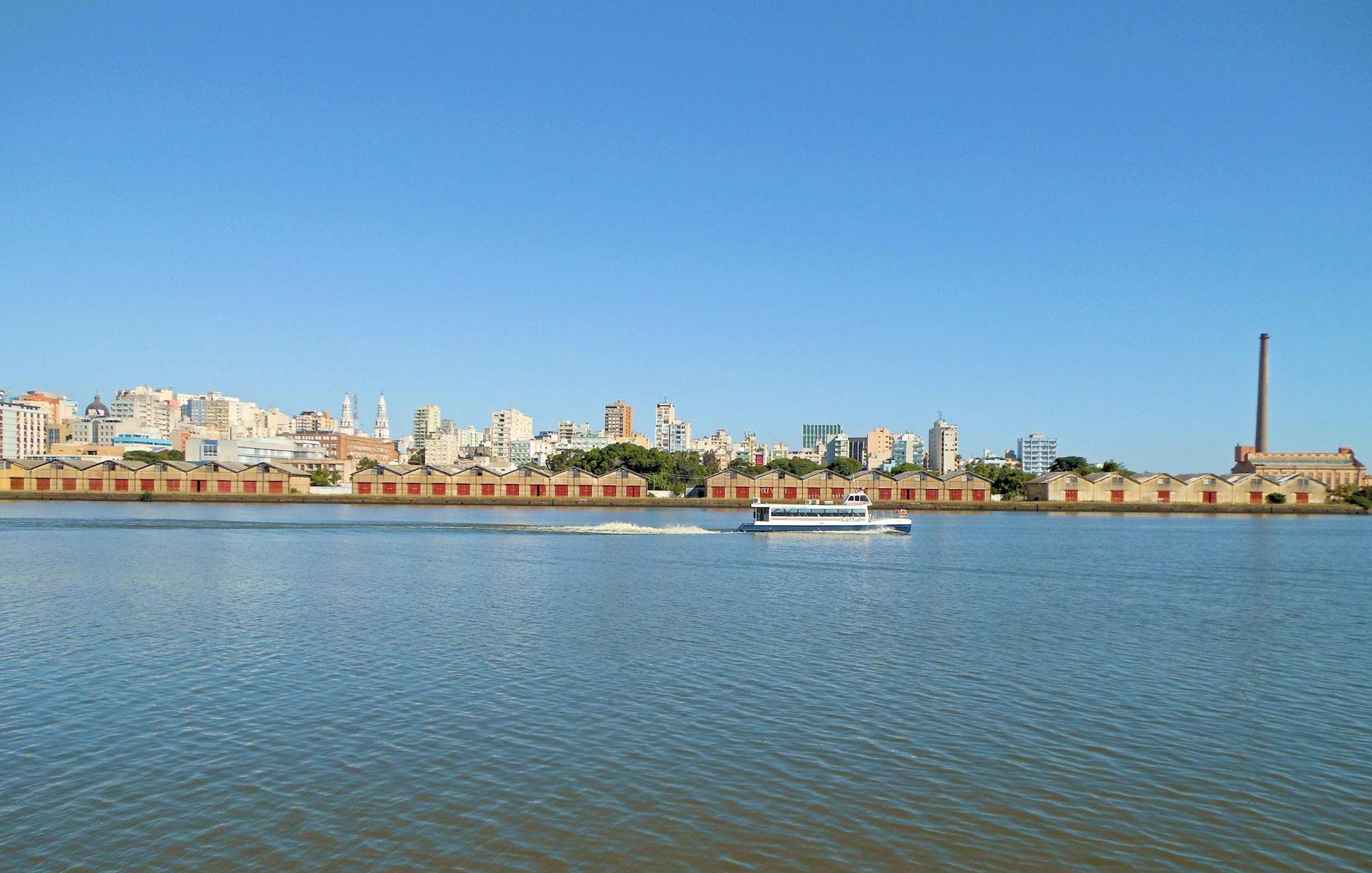 Scenic view of Porto Alegre's waterfront with city skyline and clear blue sky.