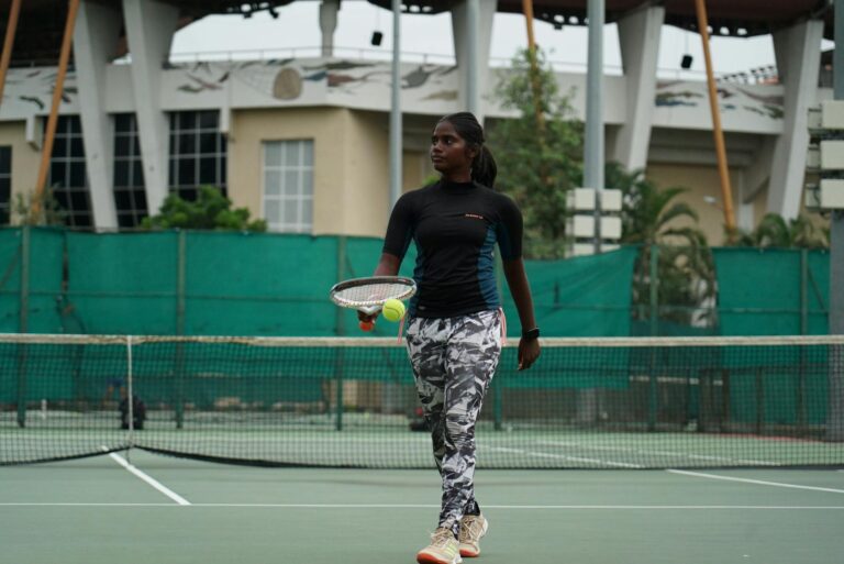 A focused young athlete practicing tennis on an outdoor court, ready to serve the ball.