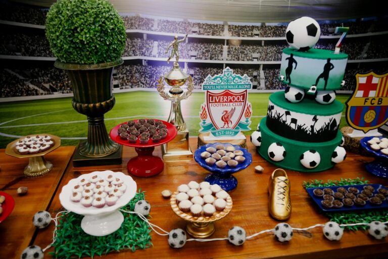 A vibrant soccer-themed dessert table featuring cakes, trophies, and decorations for a birthday party.