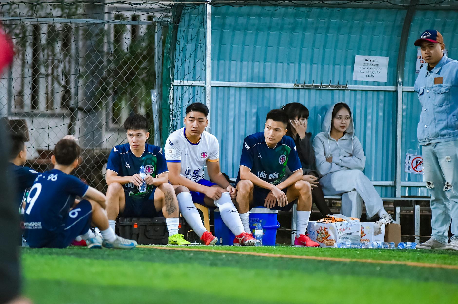 Football team and fans sitting on benches during a break in a local match in Hà Nội, Việt Nam.